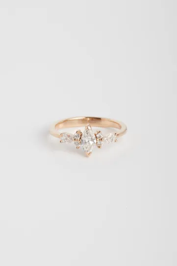 La bague Ewen S en or rose 750‰ sertie d'un diamant taille marquise et accompagné de diamants taille brillant et poire.