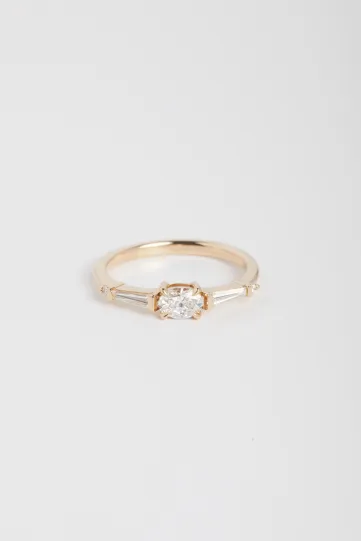 La bague Marine en or rose 750‰ sertie d'un diamant taille ovale et accompagné de diamants tapers et brillant.