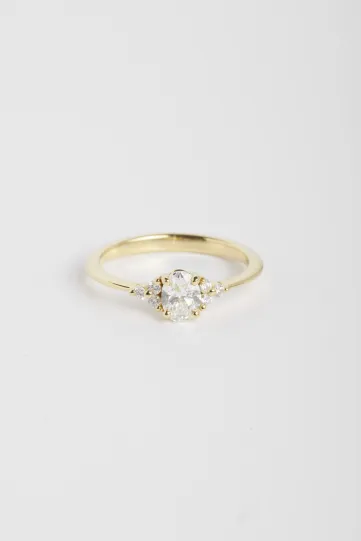 La bague Clara L, en or jaune 750‰ sertie d'un diamant central taille ovale et accompagné de diamants taille brillant.