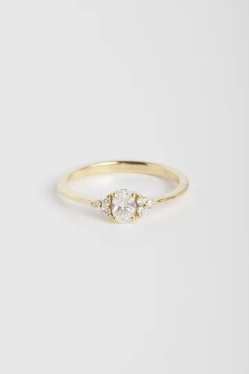 The Clara M ring, in 18k yellow gold set with an oval central diamond and accompanied by brilliant-cut diamonds.