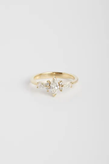 La bague Ewen S en or jaune 750‰ sertie d'un diamant taille marquise et accompagné de diamants taille brillant et poire.