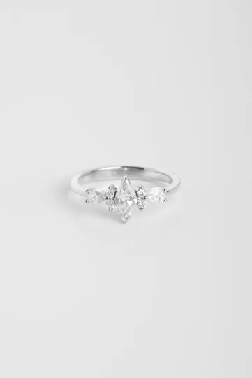 La bague Ewen S en or blanc 750‰ sertie d'un diamant taille marquise et accompagné de diamants taille brillant et poire.