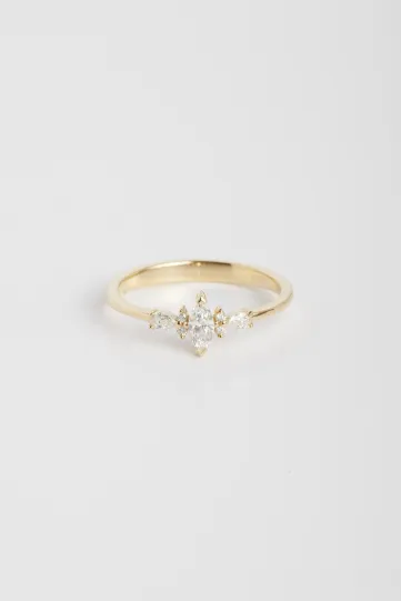 La bague Ewen XS en or jaune 750‰ sertie d'un diamant taille marquise et accompagné de diamants taille brillant et poire.