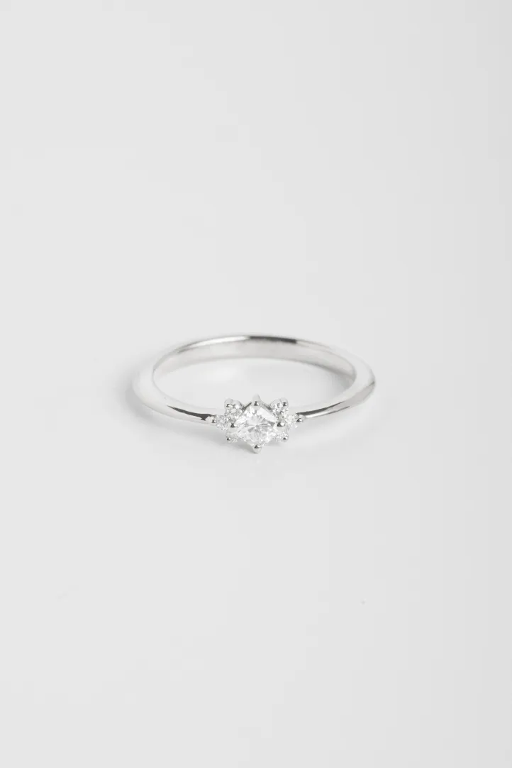 La bague Farah XS, en or blanc 750‰, sertie d'un diamant central taille coussin et accompagné de diamants taille brillant La bague Farah XS, en or blanc 750‰, sertie d'un diamant central taille coussin et accompagné de diamants taille brillant
