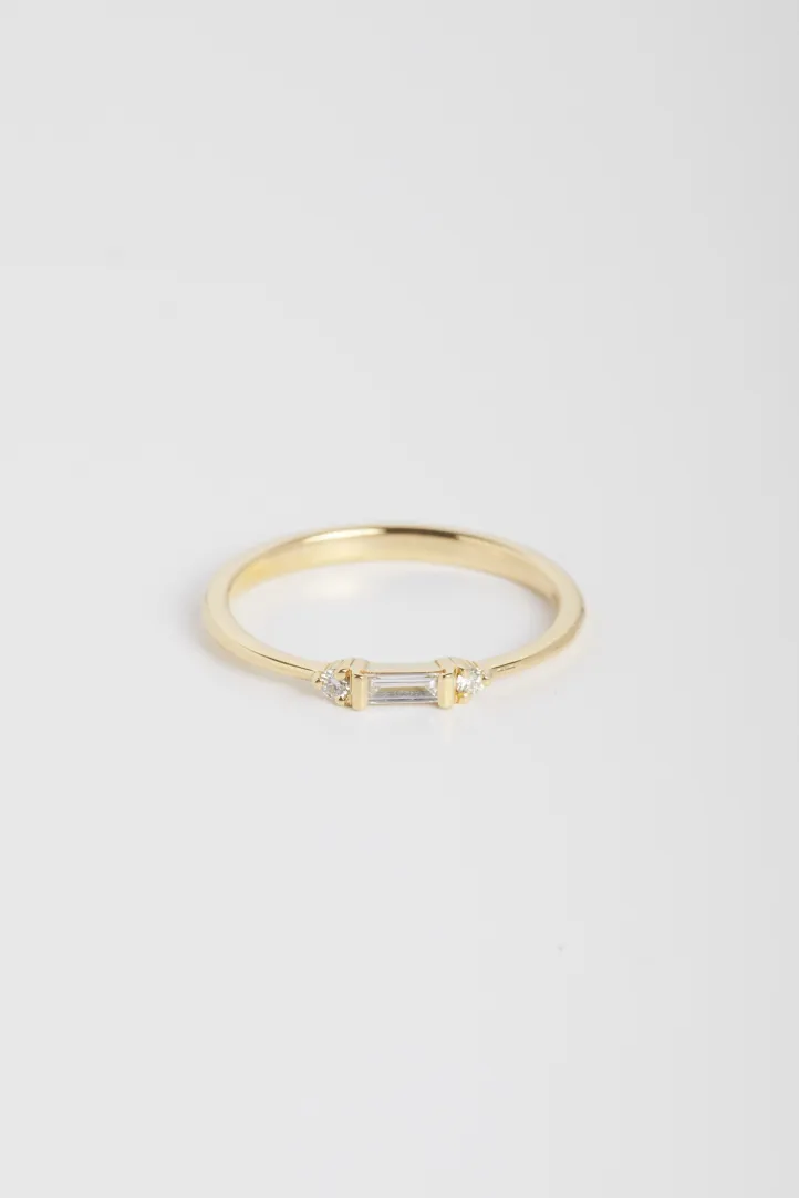 La bague Nessa, en or jaune 750‰, sertie d'un diamant taille baguette et accompagné de diamants taille brillant. La bague Nessa, en or jaune 750‰, sertie d'un diamant taille baguette et accompagné de diamants taille brillant.