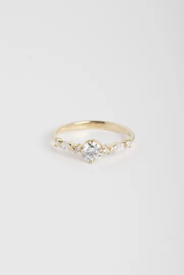 La bague Prune S, en or jaune 750‰, sertie d'un diamant central taille brillant et accompagné de diamants taille brillant et marquise.