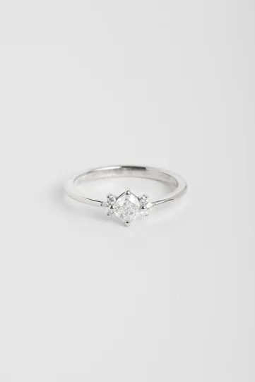 La bague Farah M, en or blanc 750‰, sertie d'un diamant central taille coussin et accompagné de diamants taille brillant