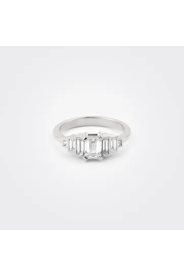 La bague Olympe en or blanc 750‰ sertie d'un diamant taille émeraude et accompagné de diamants taille baguettes.