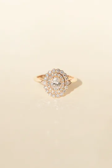 <p>La bague Aïda en or rose 750‰, sertie d'un diamant taille ovale auréolé de diamants taille brillant et poire.</p>