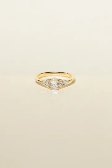 <p>La bague Julie L en or jaune 750‰ sertie d'un diamant ovale et accompagné de diamants taille poire et taille brillant.</p>