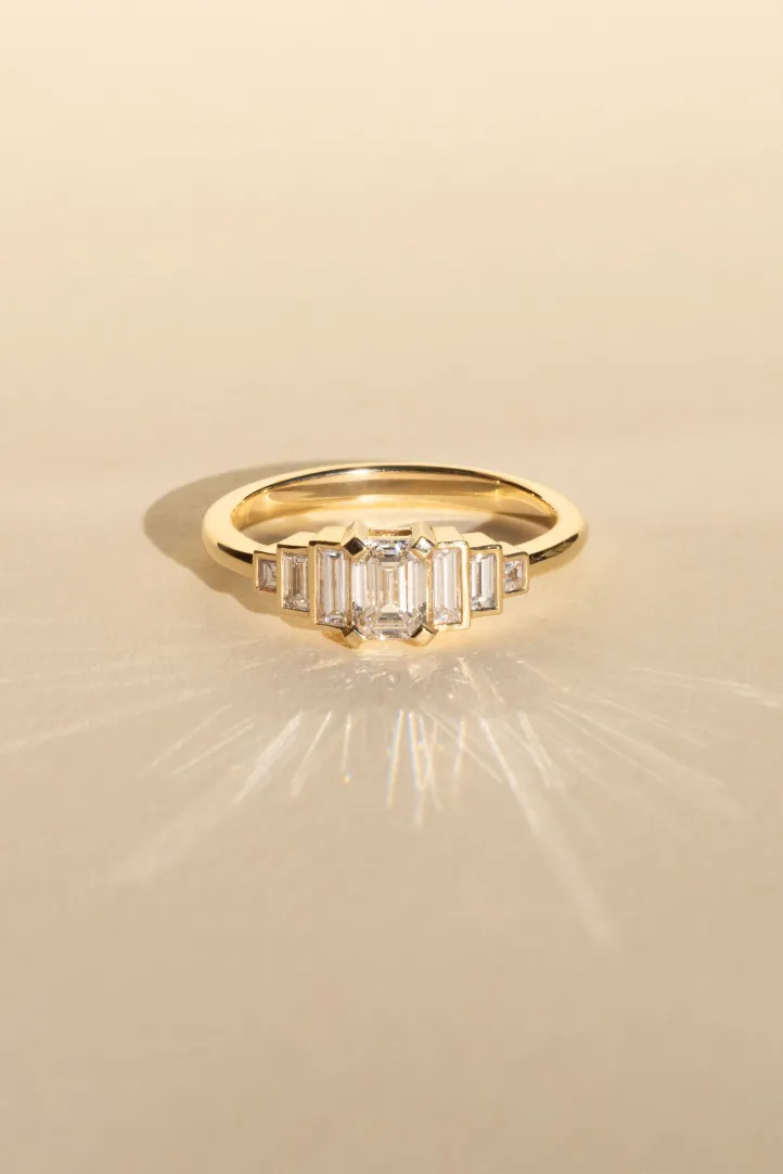 <p><span style="font-size:medium;">The Olympe ring in 18k yellow gold, set with an emerald-cut diamond and accompanied with baguette-cut diamonds.</span></p> <p><span style="font-size:medium;">The Olympe ring in 18k yellow gold, set with an emerald-cut diamond and accompanied with baguette-cut diamonds.</span></p>