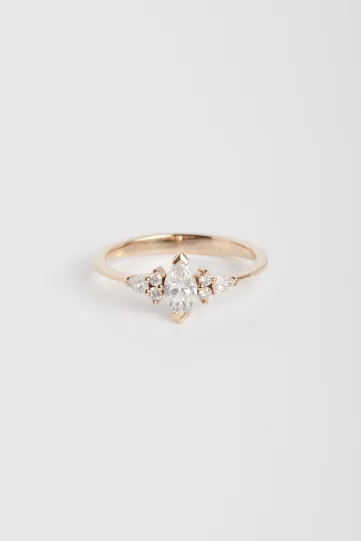 La bague Anne S en or rose 750‰ sertie d'un diamant central taille marquise et accompagné de diamants taille brillant et poire.